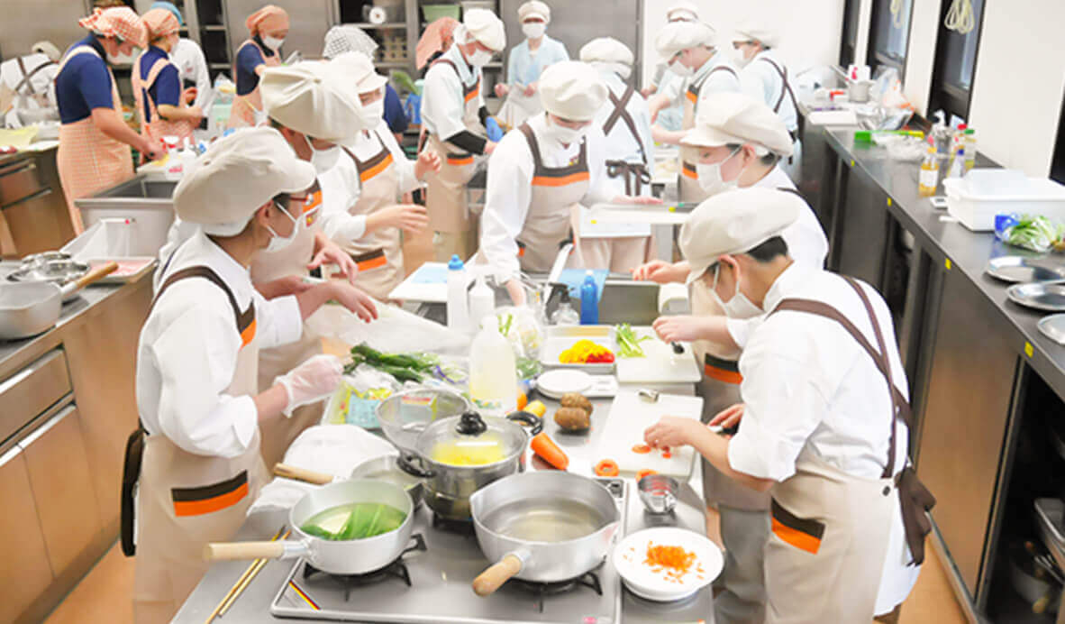 入居者がキッチンで料理体験・食事準備のレク活動に参加している様子